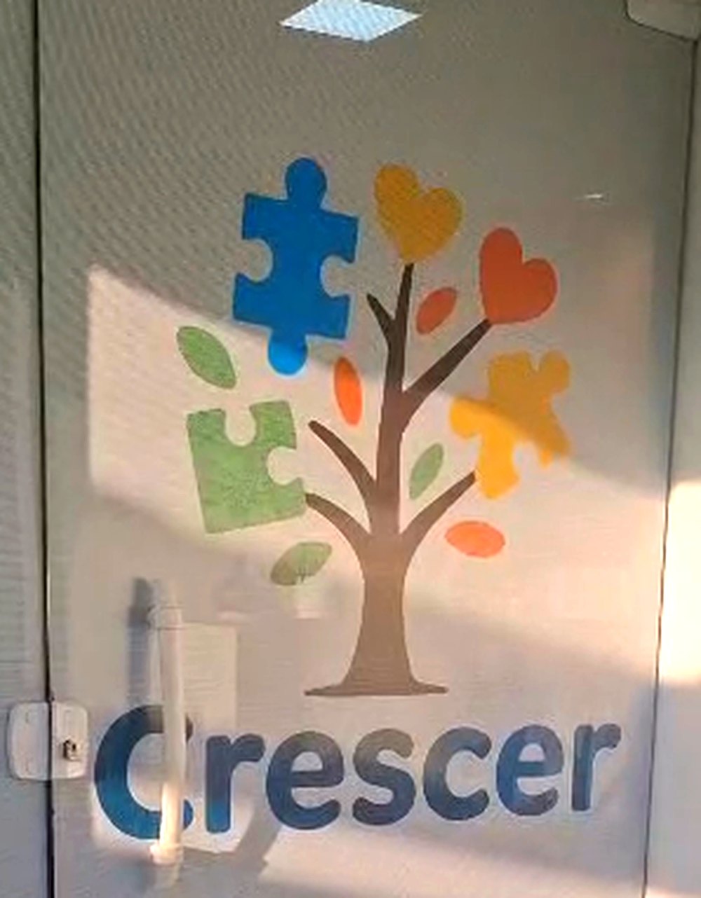 Porta de entrada de vidro com a logomarca do Espaço Terapêutico Crescer