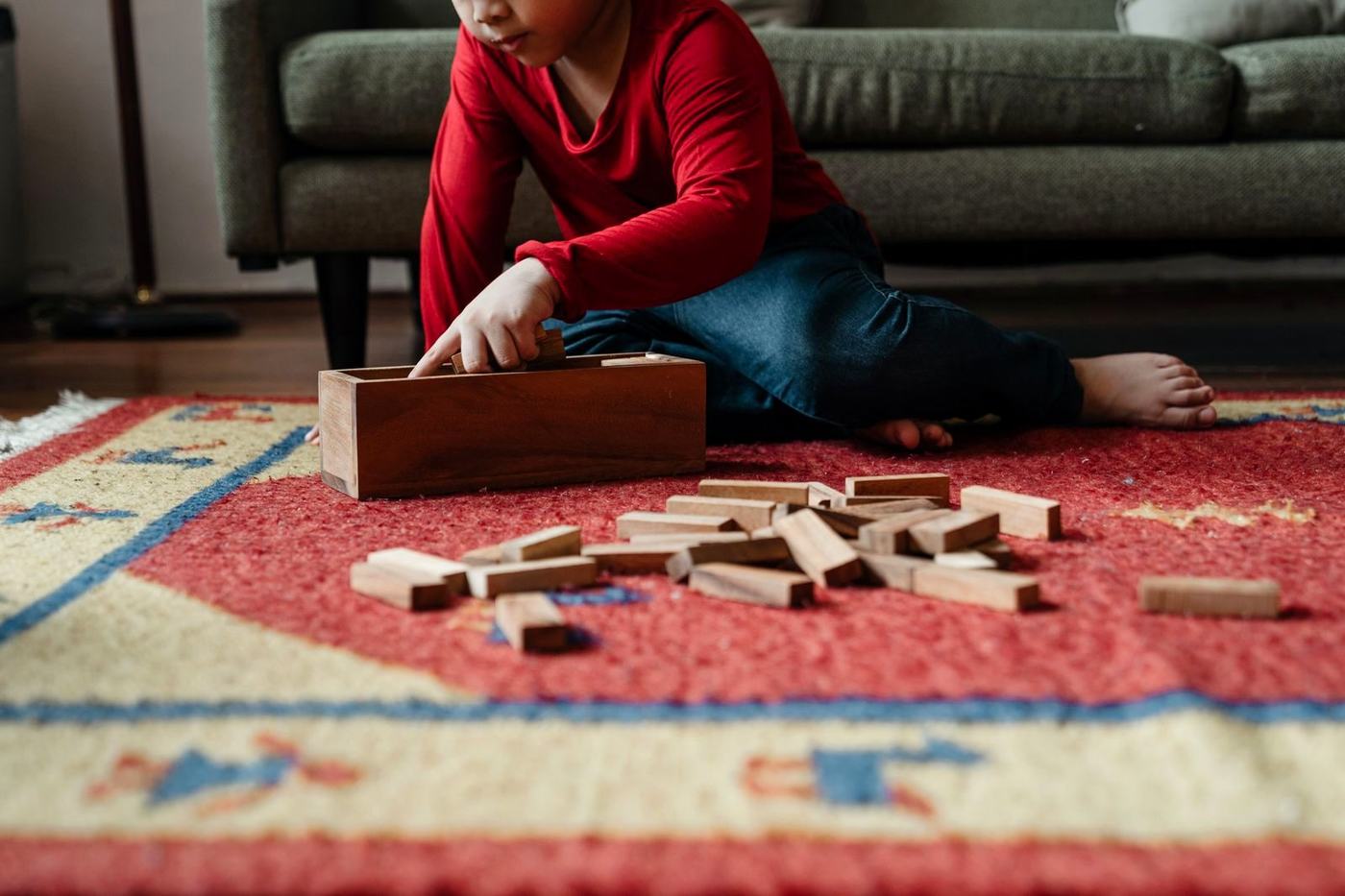 Mãe sentada no tapete de casa brincando de blocos com o filho