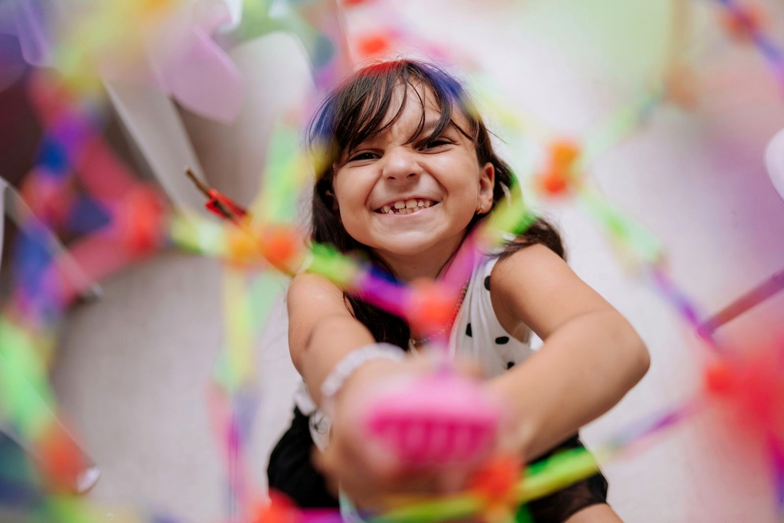 Menina sorrindo em meio a brinquedos coloridos