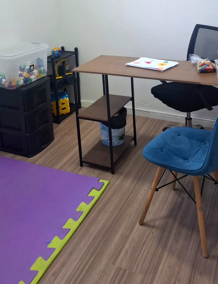Sala de atendimento com mesa, tatame e caixas de material